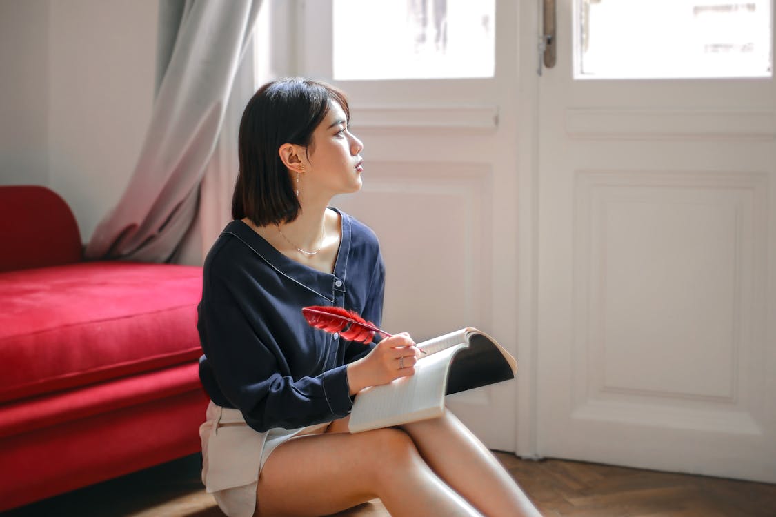 Free Thoughtful woman writing in notebook at home Stock Photo