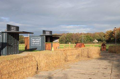 Free Rural English market scene featuring hay bales, wooden stalls and greenery in autumn light. Stock Photo