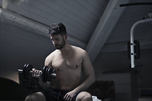Strong sportsman exercising with dumbbell