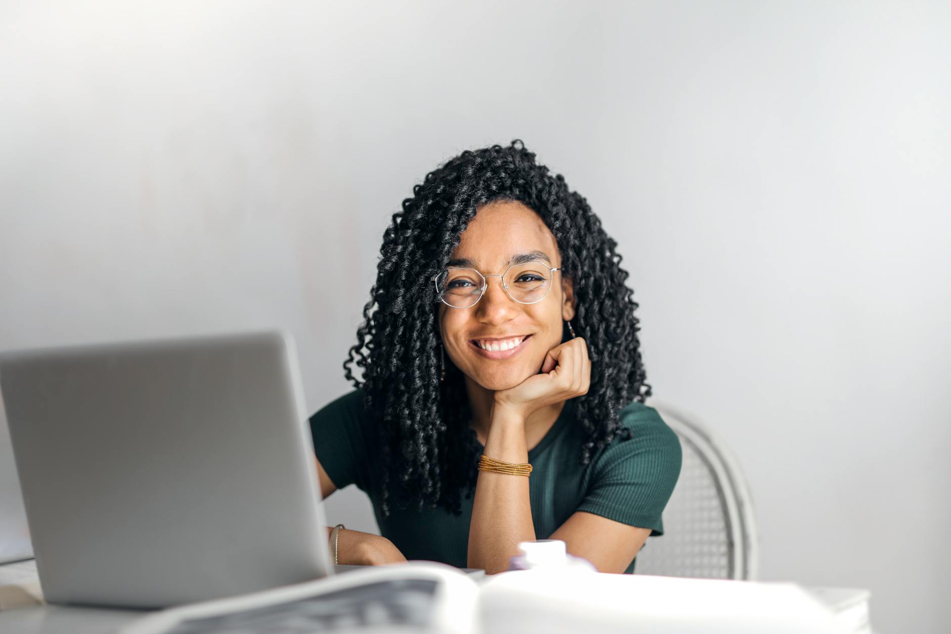 Happy Ethnic Woman Sitting at Table with Laptop