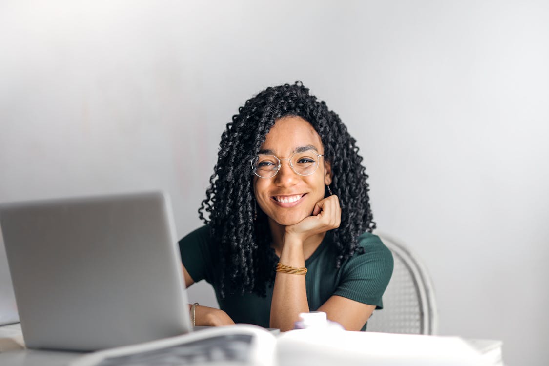 Happy young woman sitting at a table with a laptop