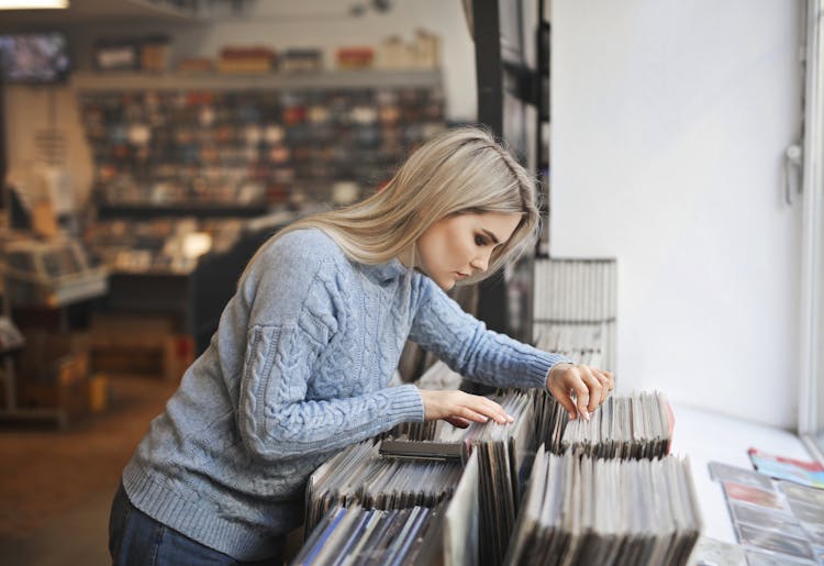 Selective Focus Side View Photo Girl In Gray Sweater Selecting Vinyl Records From A Music Store