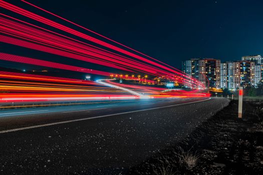 Long exposure photo of traffic light trails against a city backdrop in Ankara at night.