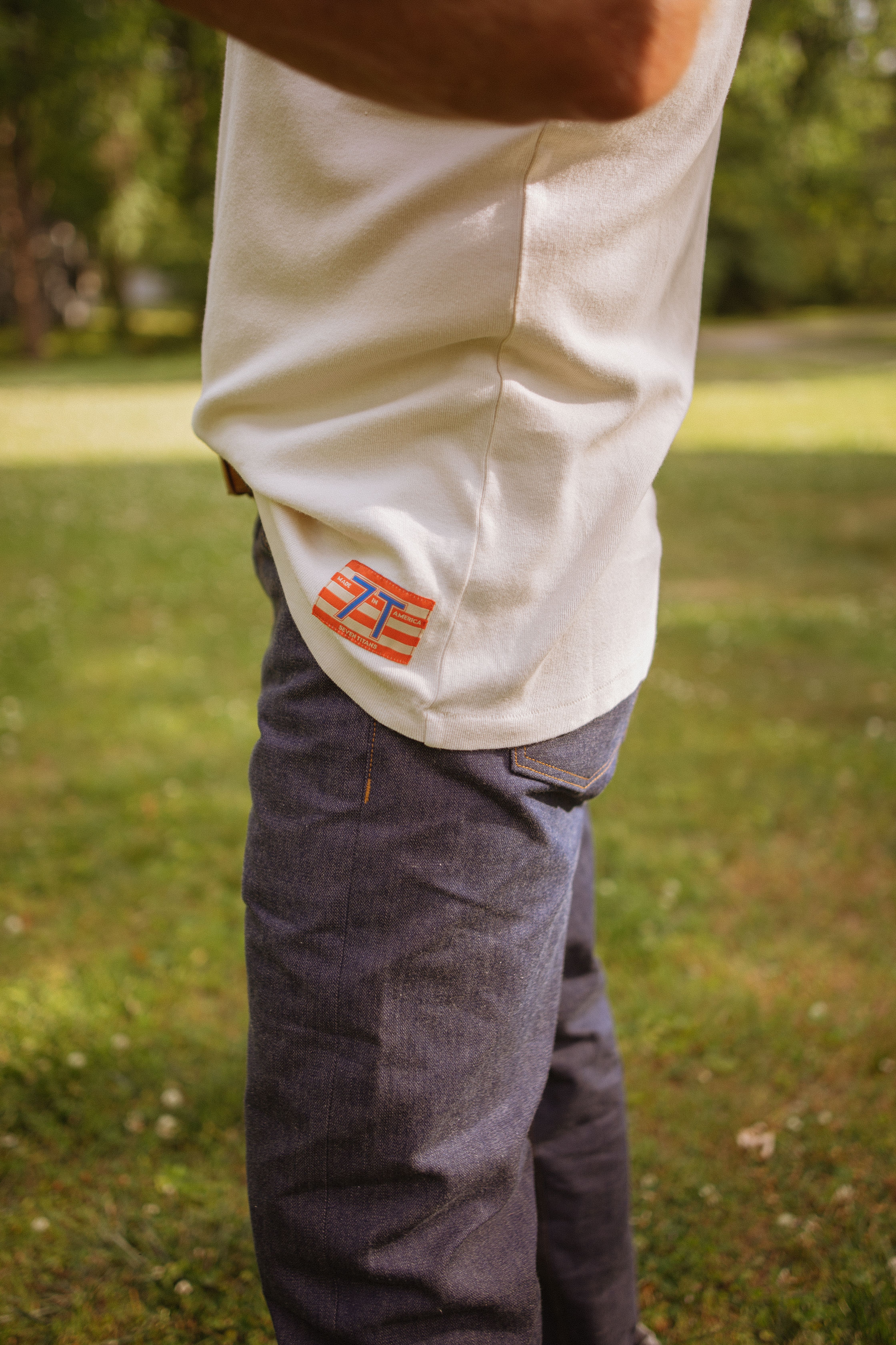 Man in a white T-shirt and denim jeans enjoying nature outdoors.