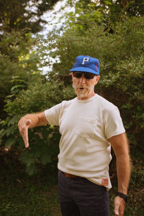 Free Stylish man in white t-shirt and cap posing outdoors in summer greenery. Stock Photo