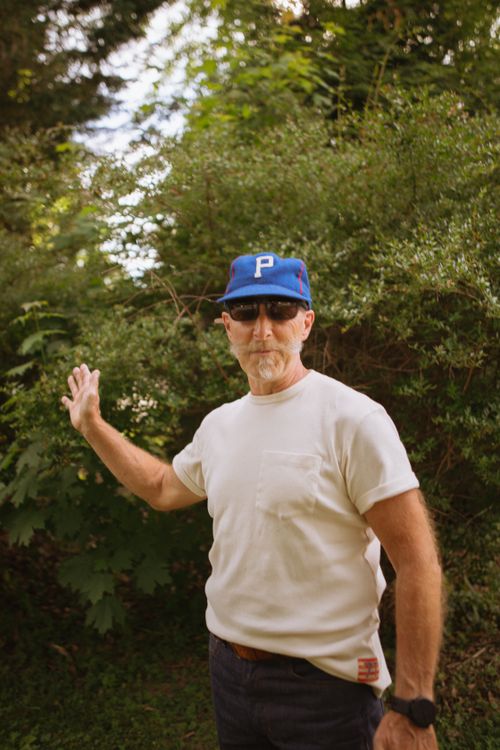 Free Man outdoors in a white t-shirt and blue cap, showcasing casual menswear style. Stock Photo