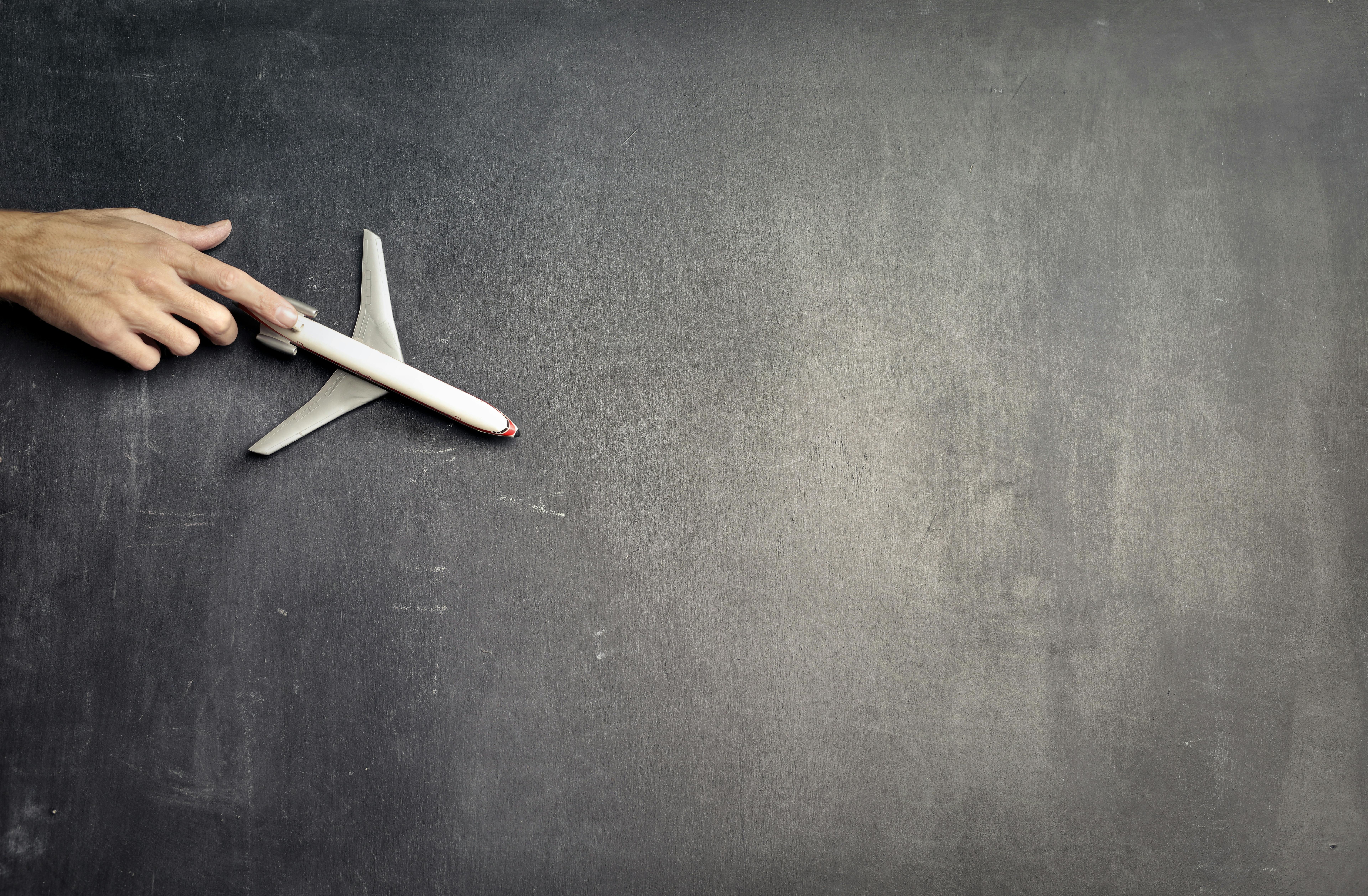 anonymous person with miniature airplane on chalkboard