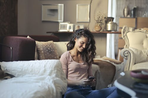 Telefonunu Kullanırken Katta Oturan Gülümseyen Kadın Fotoğrafı