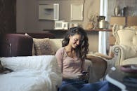 穿着休闲装的微笑女人在时尚的客厅里使用她的智能手机