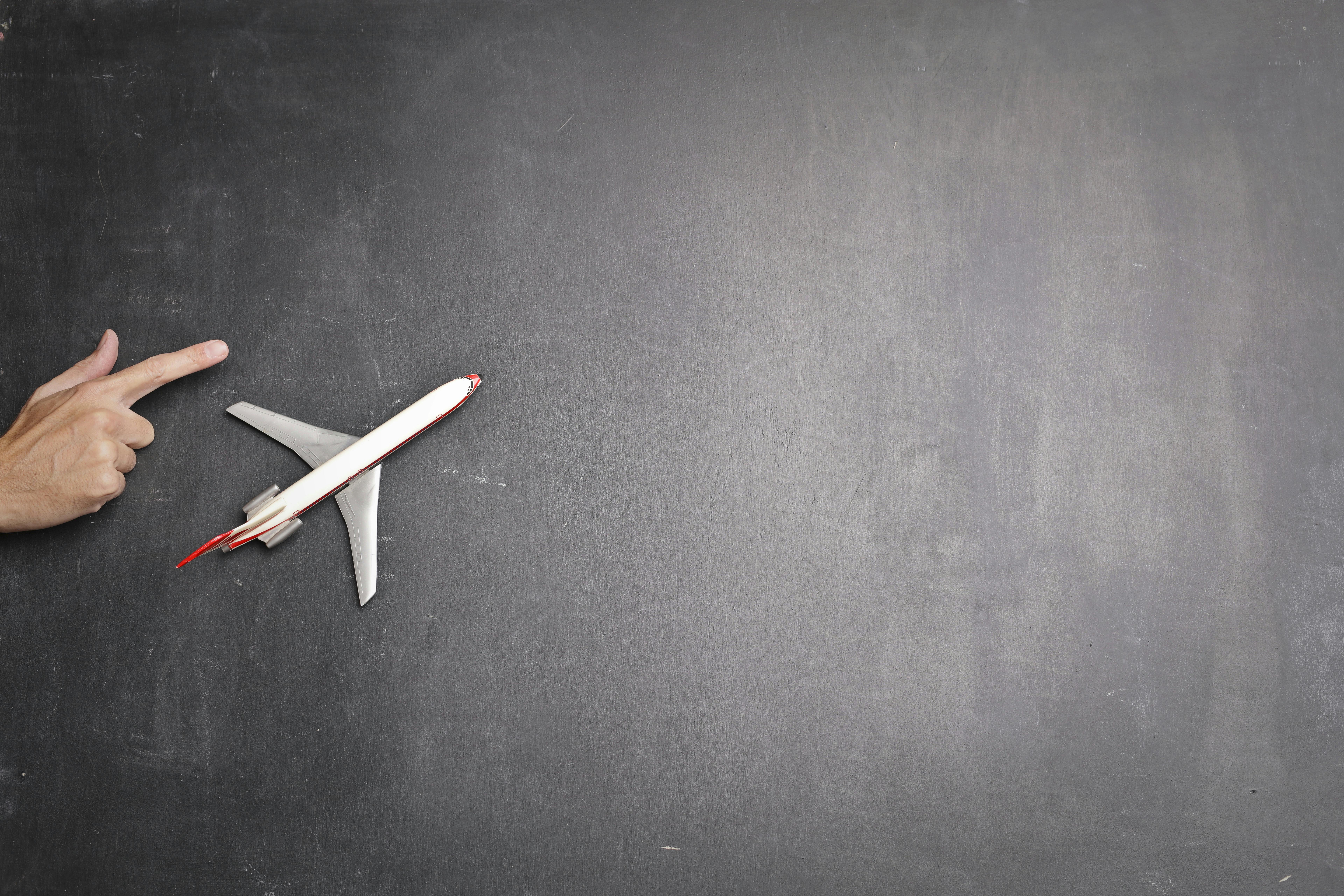 toy plane and human hand on chalkboard