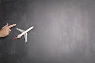 Toy plane and human hand on chalkboard