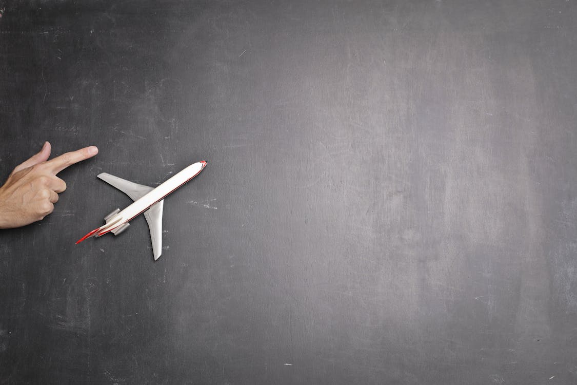 Toy plane and human hand on chalkboard