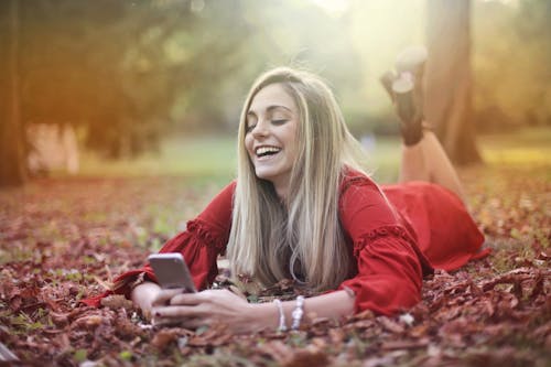 Free Woman in Red Dress Lying on Brown Dried Leaves Stock Photo