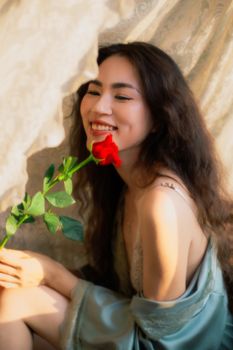 A woman enjoying a moment with a rose, bathed in gentle lighting.