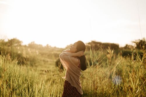 Free A serene moment captured as a woman basks in sunlight amidst vibrant greenery. Stock Photo