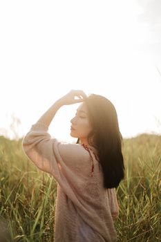 一位年轻女子在绿草茵茵的田野里静静地欣赏日落美景。