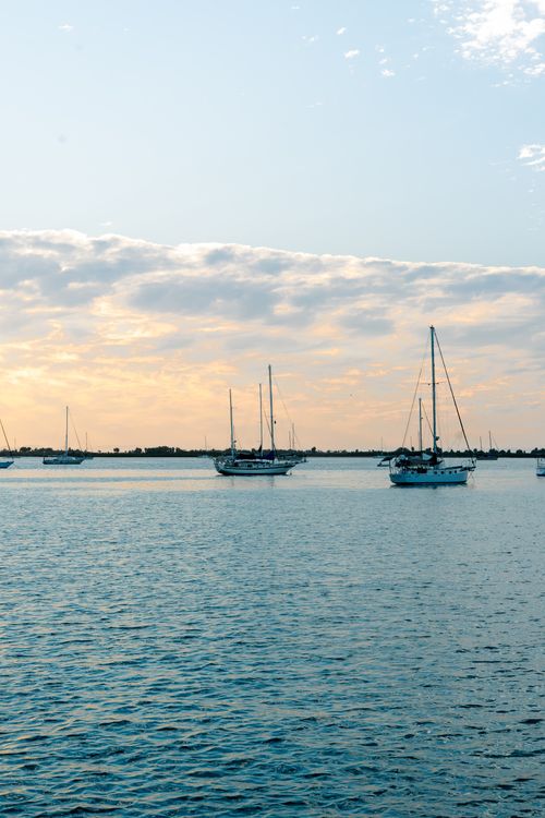 Free Peaceful sailboats floating on calm water during a beautiful sunrise, creating a serene and picturesque scene. Stock Photo