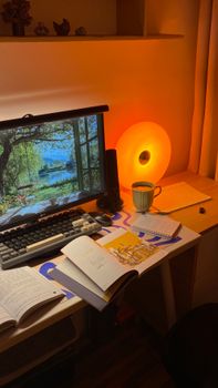 A warm and inviting home workspace with a computer, books, and ambient lighting.
