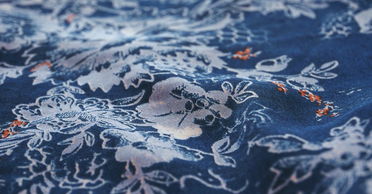 Close-up view of a blue fabric showcasing intricate white floral patterns, perfect for textile enthusiasts.