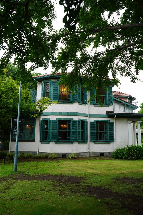 Free Colonial-style house surrounded by lush greenery in Japan, showing architectural beauty. Stock Photo