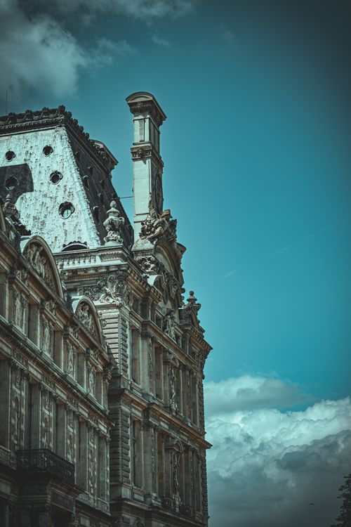 Free Close-up of the Louvre Museum's architectural details against a clear blue sky in Paris, France. Stock Photo