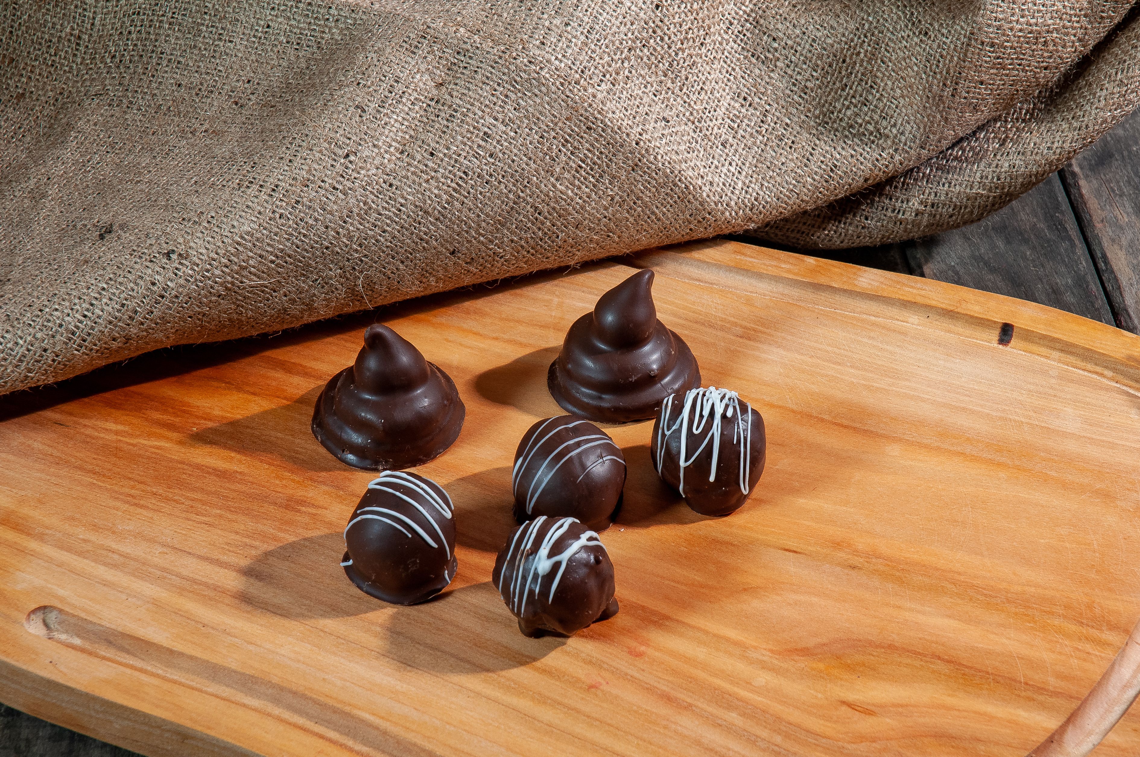 Delicious chocolate truffles arranged on a wooden board with a rustic burlap backdrop.