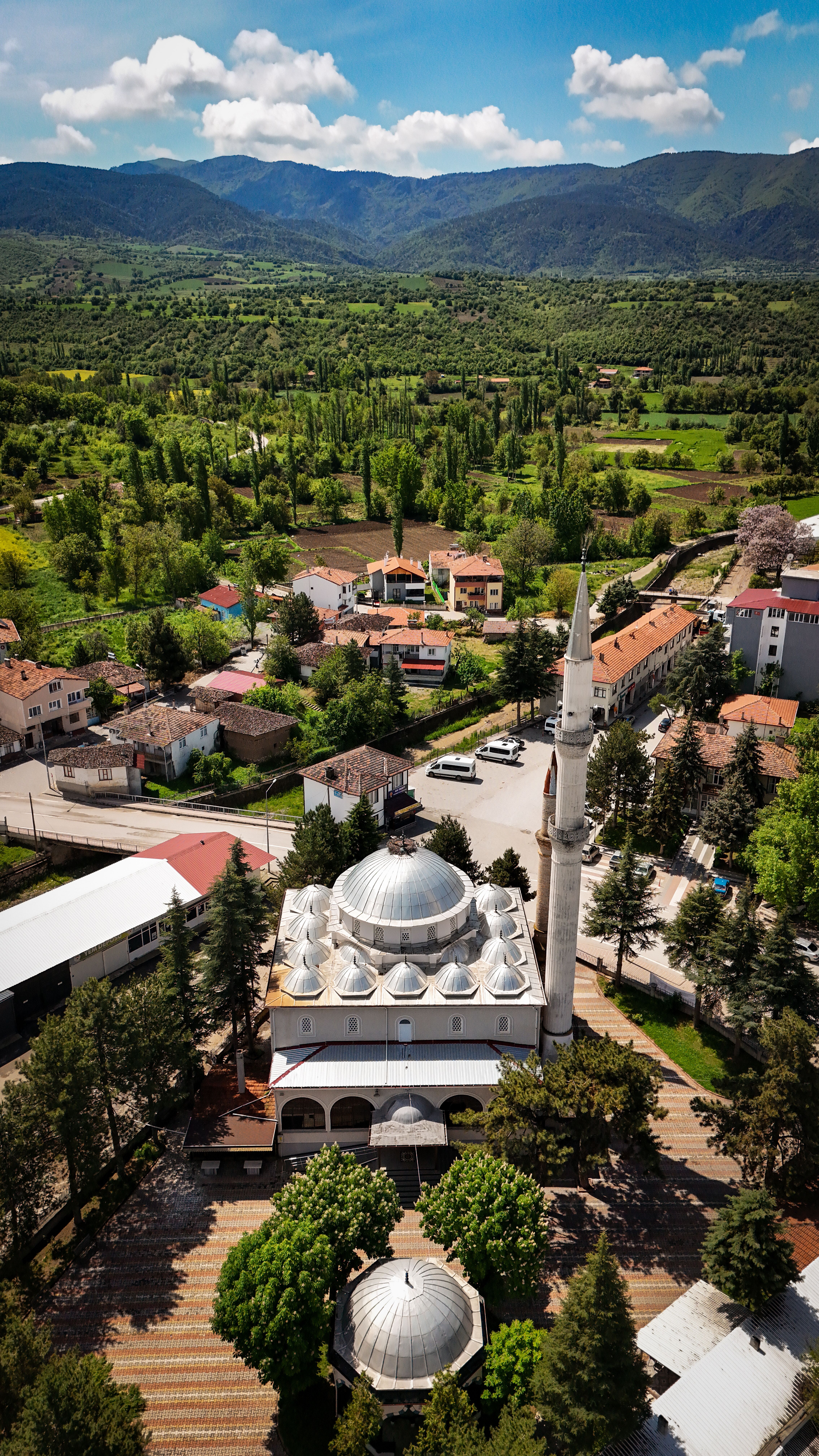Aerial shot of a mosque surrounded by lush greenery in Hamamözü, Türkiye.