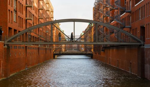 Free Two people crossing a historic bridge in the iconic Speicherstadt district of Hamburg, Germany. Stock Photo