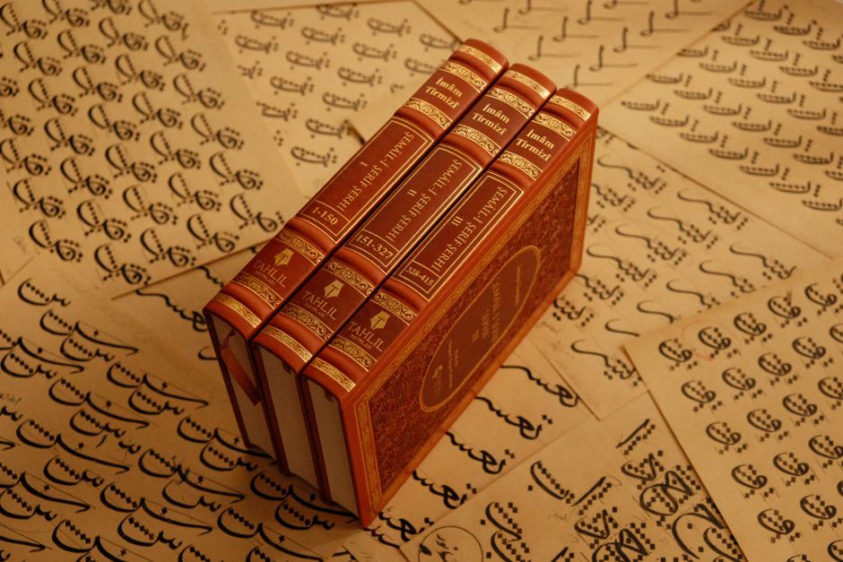 A stack of vintage books titled 'Imam-i Tirmizi' placed on traditional script pages.
