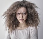 一位卷发女子面露怒容的肖像，非常适合情感类内容