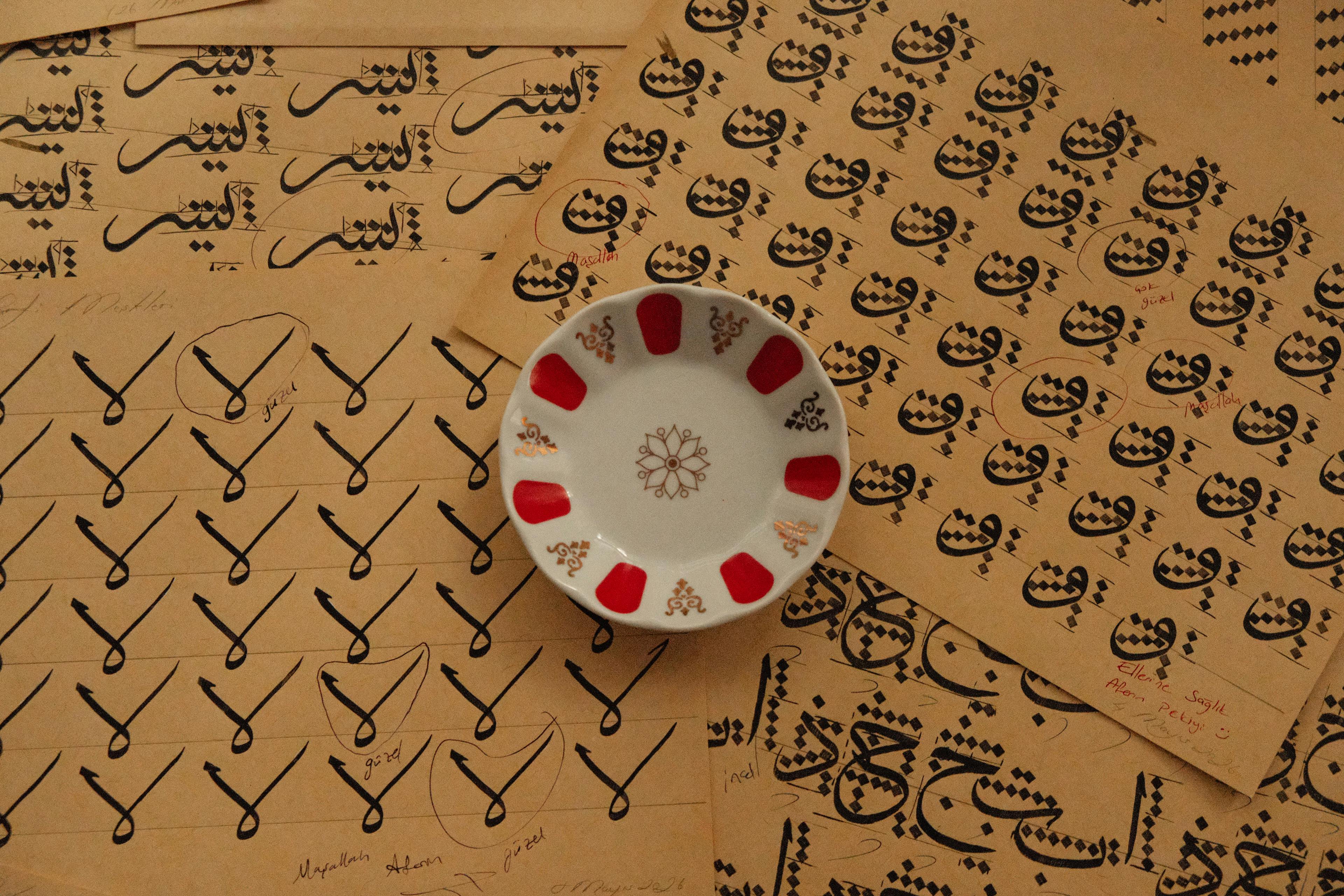 Intricate Arabic calligraphy practice sheets with a decorative plate on brown paper background.