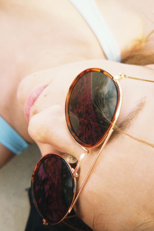 Free Artistic angle of a woman with sunglasses lying down outdoors, embodying summer relaxation. Stock Photo
