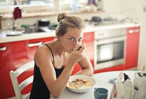 無料 黒のタンクトップのシリアルを食べる女性 写真素材