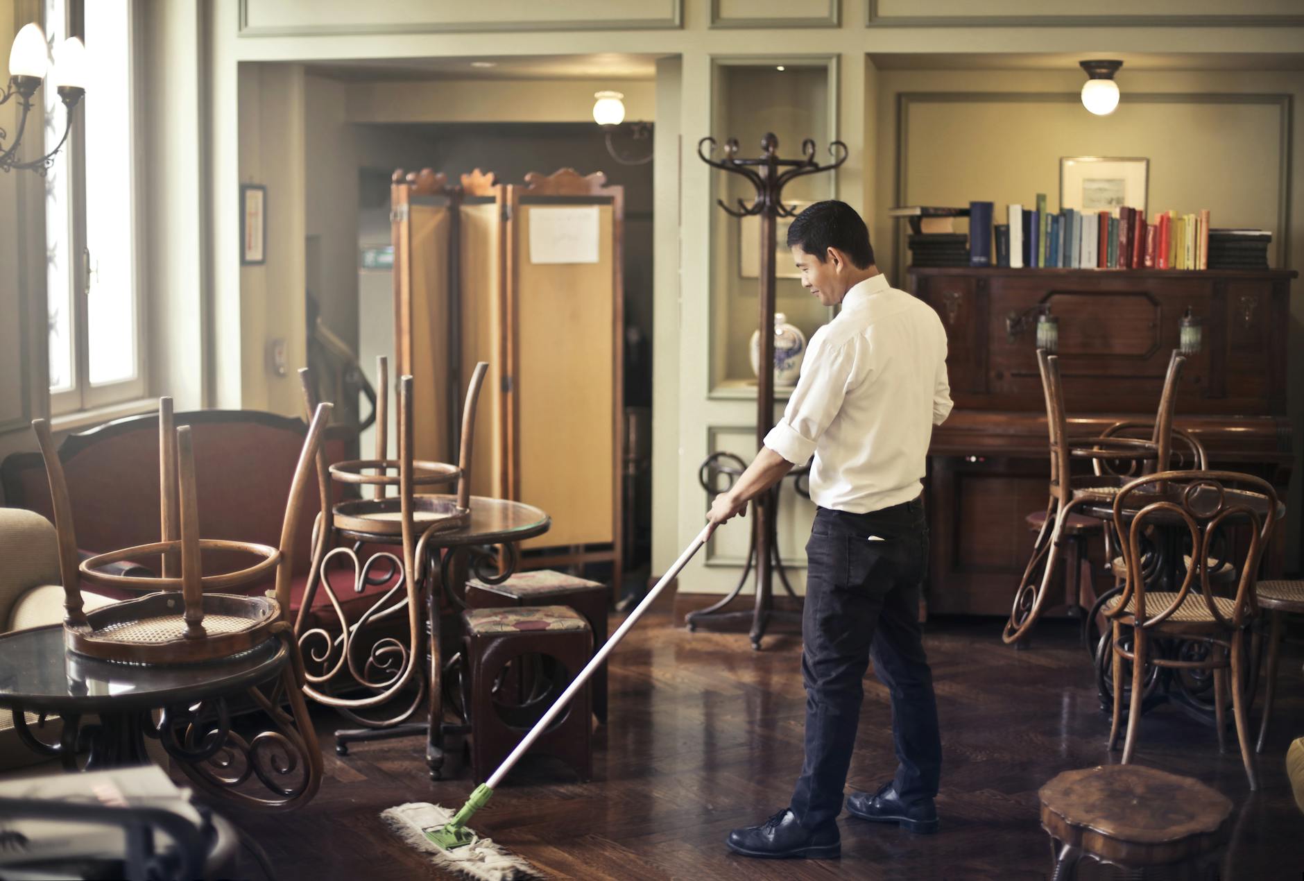 Male employee cleaning floor in restaurant