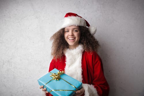 Free Young Child in Red  Santa Hat Holding Blue Christmas Present Stock Photo