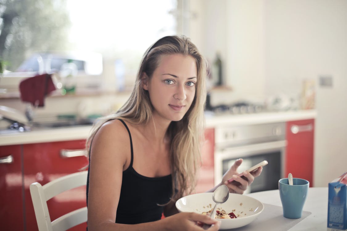 オートミールを食べる黒いタンクトップの女性