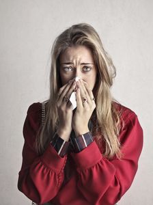 Woman sneezing into a tissue