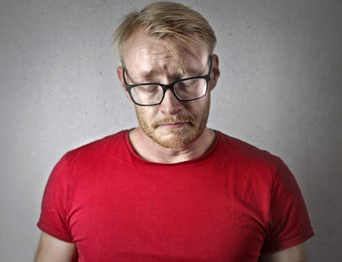 Portrait Photo of a Sad Man in a Red T-shirt and Black Framed Glasses
