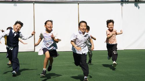Free Happy children enjoying outdoor play, running on green grass under bright sunlight. Stock Photo