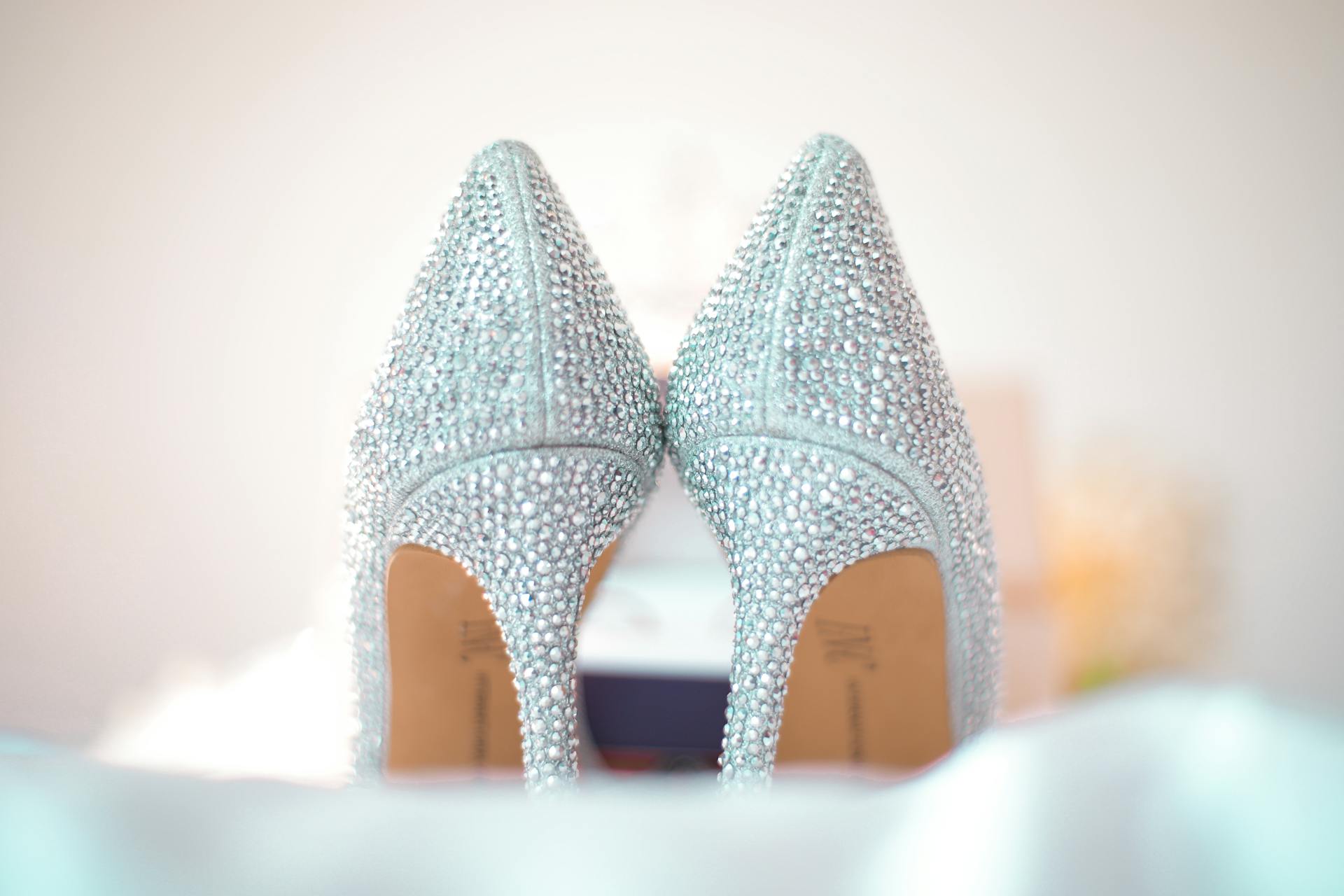 Stylish wedding high heels decorated with shiny silver rhinestones placed on white fabric