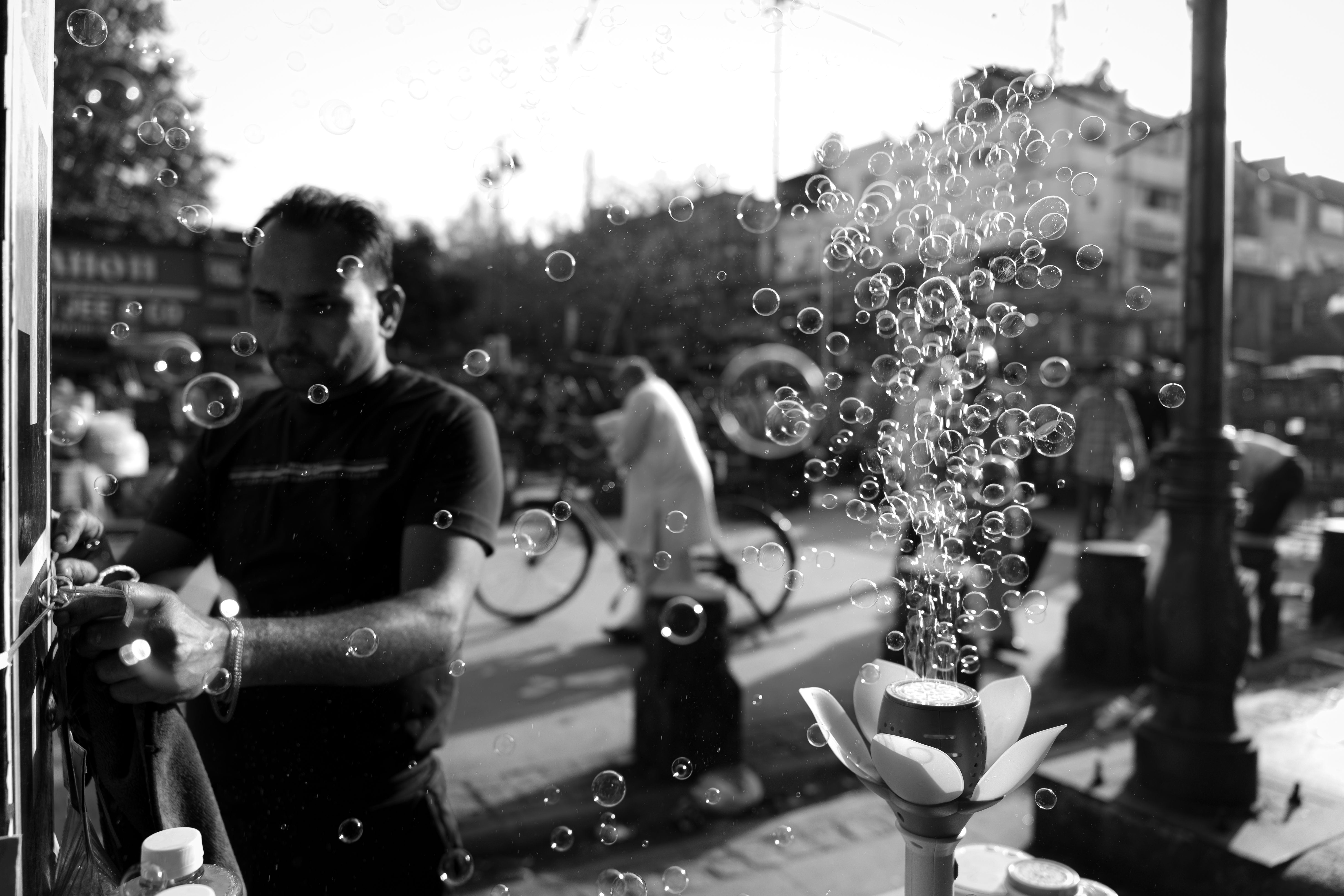 Black and white street photo showing a vendor with bubbles floating around, capturing urban life.