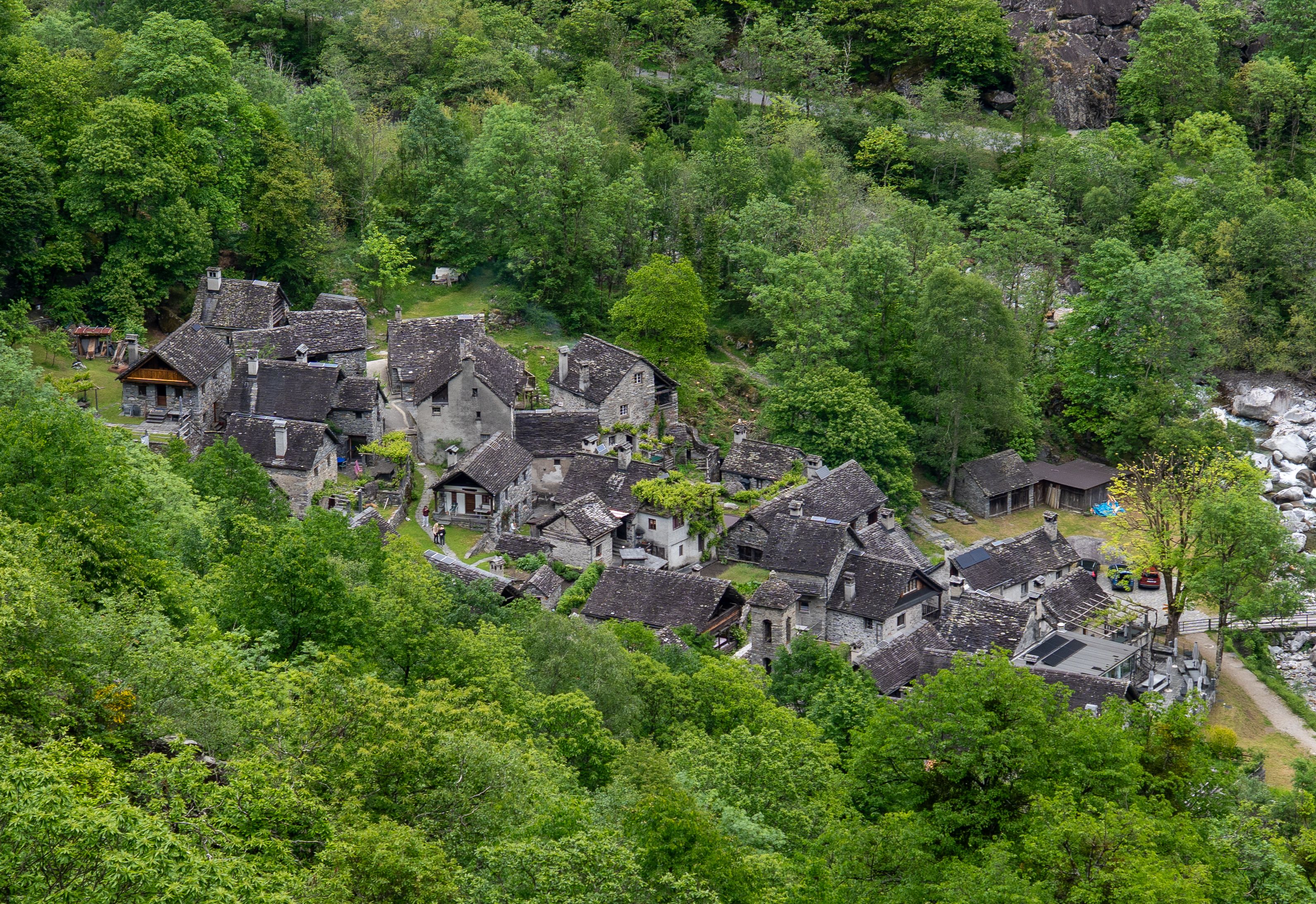 Aerial view of charming stone houses in Cevio, Ticino, surrounded by lush greenery.