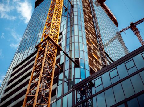 Dynamic view of skyscraper construction with cranes in Wrocław, Poland on a sunny day.