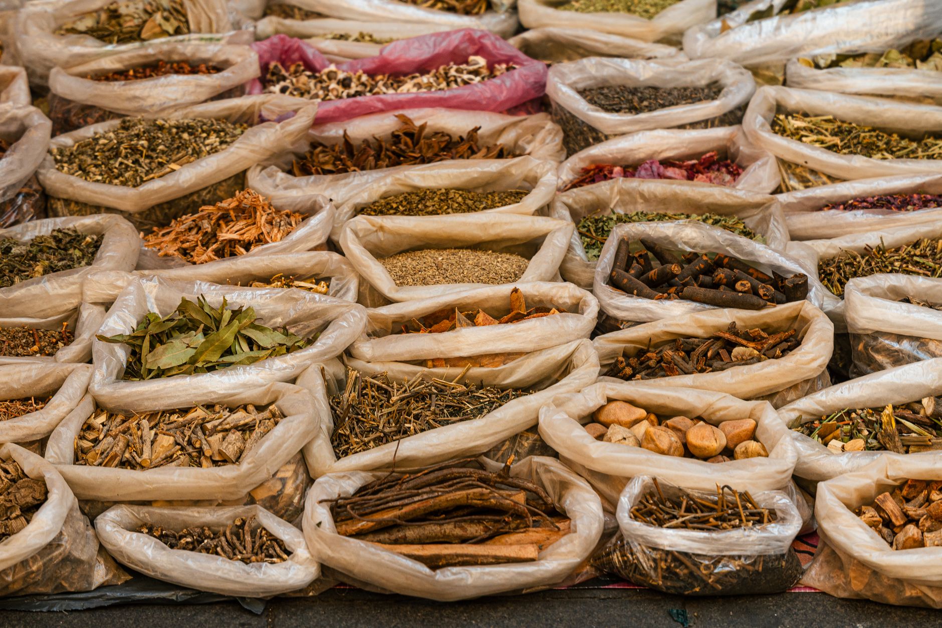 A collection of spices and dried herbs displayed in bags at a market, offering a colorful aroma.