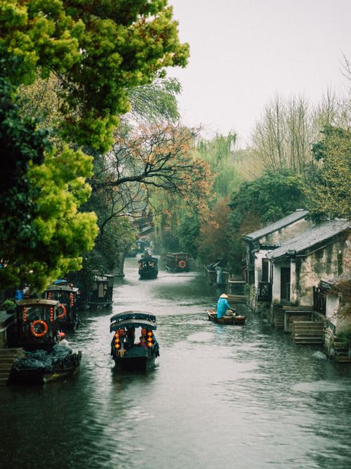 Free Scenic view of a canal with boats in a traditional village, surrounded by lush greenery. Stock Photo