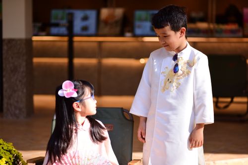 Free Two children in traditional Asian clothing indoors, engaging in a conversation. Stock Photo
