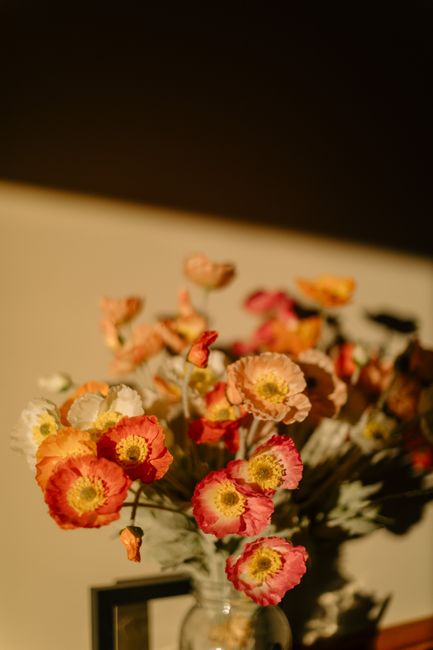 A vase of vibrant poppies bathed in warm afternoon sunlight, creating a soft and inviting scene.