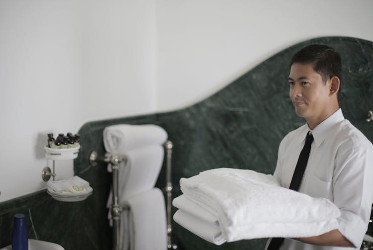 Hotel Servant With Clean Towels In Bathroom