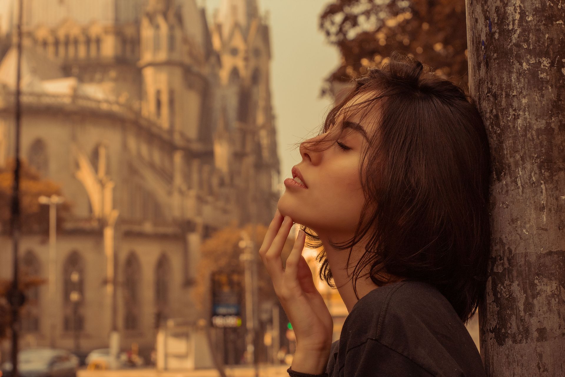 Selective Focus Side View Photo of Woman in Black Shirt Leaning Against Metal Lamp Post Posing With Her Eyes Closed