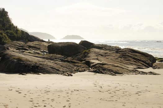 Tranquil view of rocks and ocean on a sunny day at Guaratuba Beach, Paraná, Brazil.